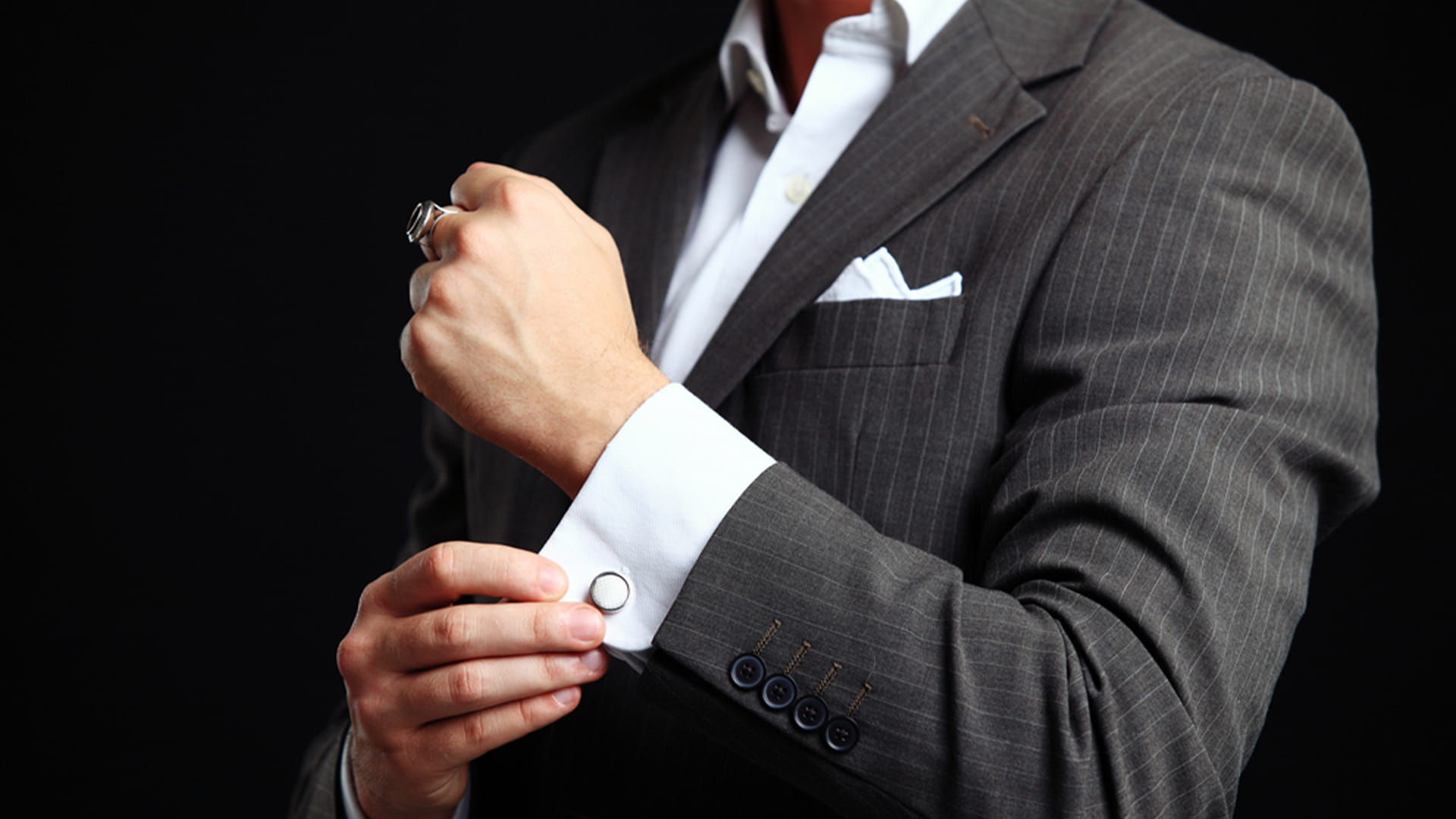 Businessman in a tailored suit adjusting cufflinks, symbolising a well-maintained formal wear