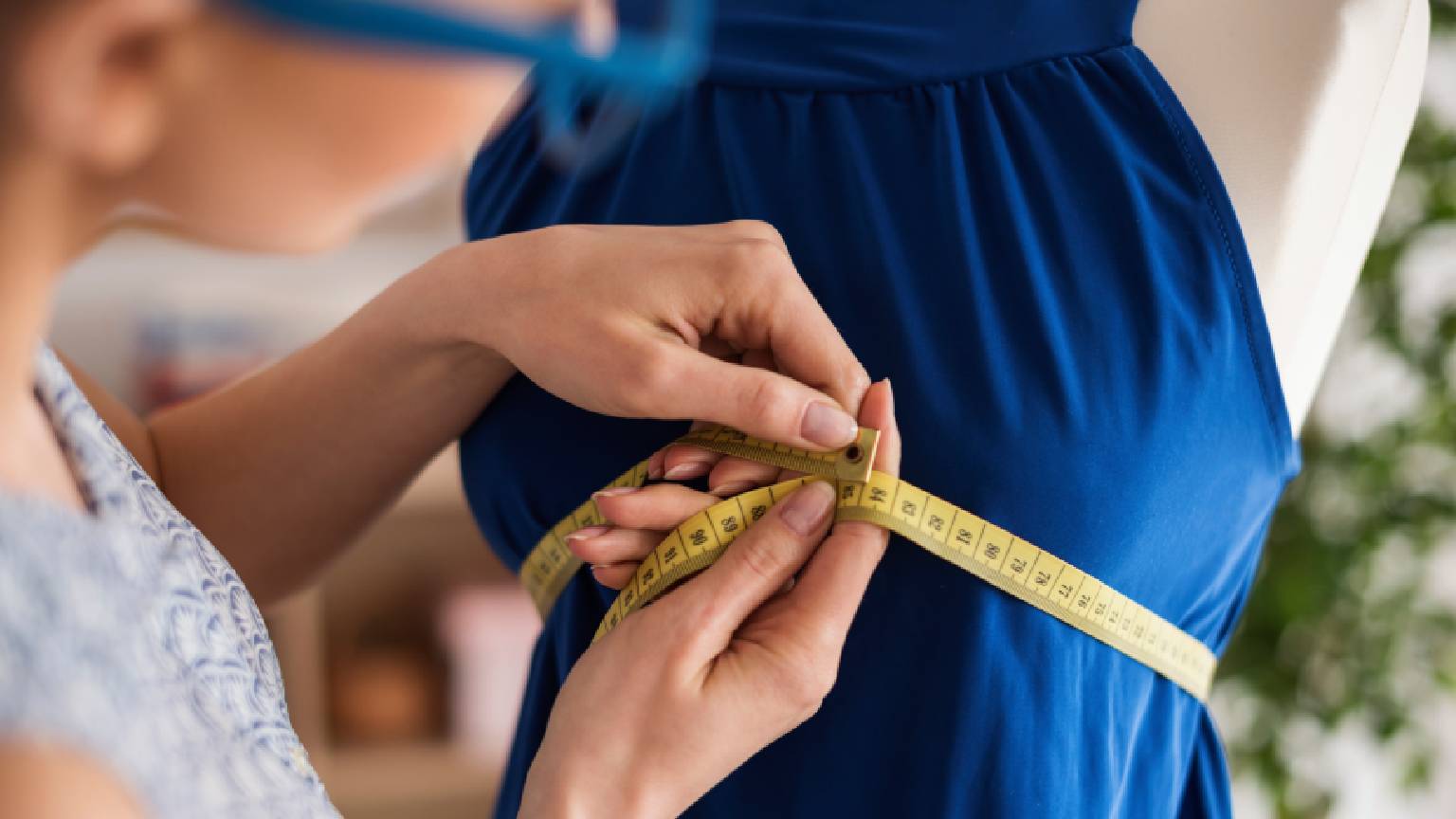 Bridesmaid dress alterations measuring the waist fit of a blue formal gown